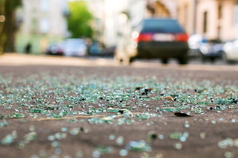Shards of broken car glass scattered across a street after a vehicle accident or break-in.